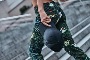 Best summer accessory. Close-up of young woman carrying a cap while going up the stairs outdoors photo