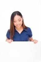 Curious beauty. Beautiful young Asian woman looking at copy space and smiling while standing isolated on white photo