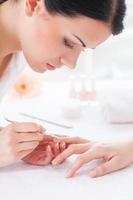 Manicure master at work. Close-up of beautician preparing customers fingers for manicure photo