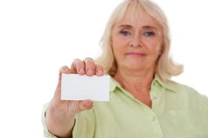 Copy space on her card. Serious senior woman showing her business card while standing isolated on white background photo