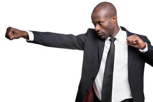 Elegant and cool. Side view of serious young African man in formalwear fighting with someone while standing isolated on white background photo