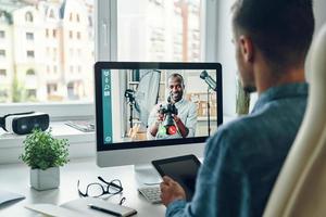 Busy young man talking to collegue by video call while sitting in office photo