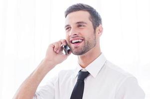 Good business talk. Happy young man in shirt and tie talking on mobile phone and smiling photo