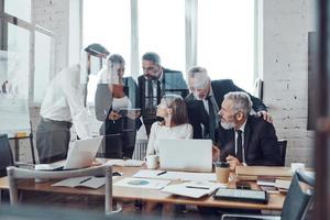 Self-driven business team analyzing sales using modern technologies while having staff meeting in the board room photo