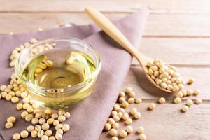 Soybean oil put in a glass cup. and soybeans on a wooden table, natural healthy food - top view photo