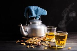 Chrysanthemum tea and Chrysanthemum flowers in a basket on a wood background. Healthy beverage for a drink. Herbs and medical concepts. photo