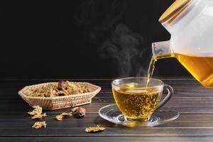 Chrysanthemum tea and Chrysanthemum flowers in a basket on a wood background. Healthy beverage for a drink. Herbs and medical concepts. photo