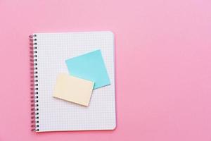 School spiral notebook on a pink background stickers lie on top of the sheet. photo