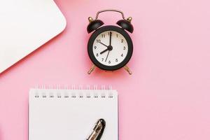 Laptop and white notepad with pen and black alarm clock, arrows point to photo