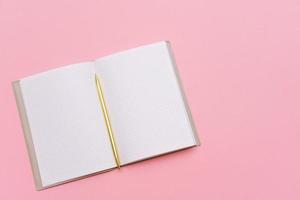 Notepad and gold pen on a pink background. Mock up, top view, copy space. photo