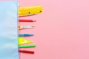 Pink background and multicolored school supplies. Back to school. Flat lay photo
