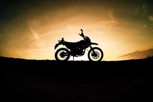 parque de silueta de motocross de motocicleta turística en la montaña por la noche. concepto de viaje de aventura foto