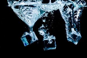 cubos de hielo en agua con burbujas sobre fondo negro foto