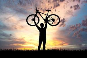 Man holds a bicycle on top of a mountain. concept of success and victory photo