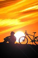 A silhouette of a cyclist descending from the mountain in the evening. photo