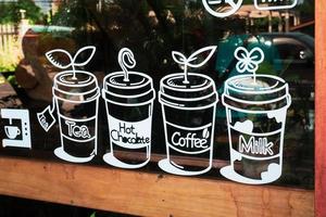 pegatinas adheridas al vaso de una cafetería en tailandia. decorando el frente de la cafetería con pegatinas. foto
