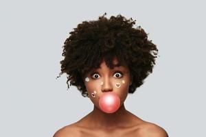 What just happened Surprised young African woman blowing the balloon while standing against grey background photo