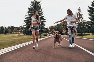 In one direction. Full length of beautiful young couple running with their dog while spending time outdoors photo