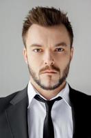 Portrait of success and confidence. Portrait of confident young man in formalwear looking at camera while standing against grey background photo