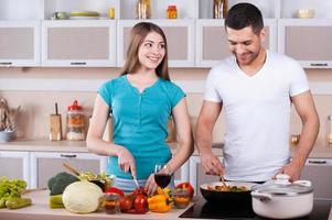 pareja cocinando juntos. feliz pareja joven cocinando juntos en la cocina foto