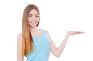 Copy space on her hand. Cheerful teenage girl holding a copy space and smiling while standing isolated on white photo