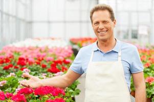 Flowers presentation. Portrait of handsome mature man standing in flower bed and gesturing photo