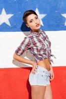 Looking cool. Beautiful young short hair woman posing against American flag background and looking at camera photo