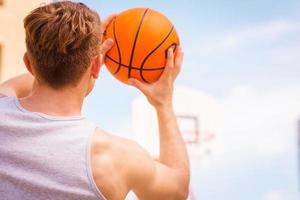 acción de tiro de baloncesto. vista trasera del joven jugador de baloncesto masculino listo para el tiro foto