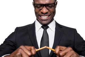 Stressed and overworked. Furious young African man in formalwear breaking pencil and grimacing while standing isolated on white background photo