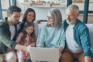 la familia moderna pasa tiempo juntos y sonríe mientras se sienta en el sofá de casa foto