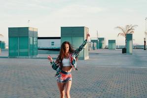 solo baila. atractiva mujer joven sonriendo y bailando mientras corre al aire libre foto