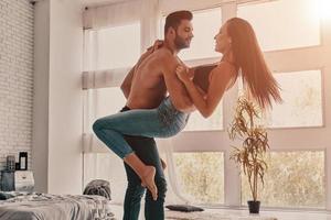 pareja disfrutando bailando. toda la longitud de una hermosa pareja joven abrazándose y sonriendo mientras bailaba en el dormitorio foto