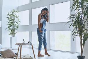 Young and beautiful. Full length of attractive young woman keeping hand in hair and smiling while walking in the bedroom at home photo