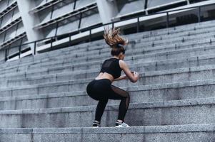 Full of energy. Modern young woman in sport clothing jumping while exercising on the stairs outdoors photo