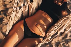 She is perfect. Close-up top view of young woman lying down in hammock while spending carefree time on the beach photo