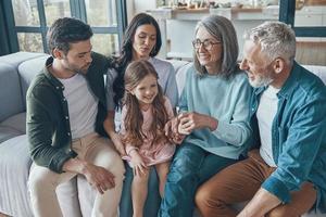 familia feliz pasando tiempo juntos y sonriendo mientras se sienta en el sofá en casa foto