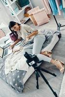 Top view of beautiful young woman in casual clothing making social media video while spending time at home photo