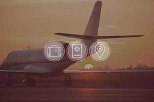 Good time for travelling. Digitally composed icon set over a picture of private jet landing in sunset photo