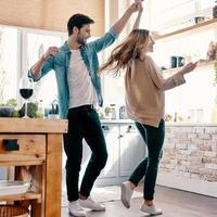 feliz y enamorado. toda la longitud de una hermosa pareja joven con ropa informal bailando y sonriendo mientras está de pie en la cocina en casa foto