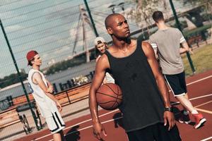 Another break. Young African man in sports clothing looking away while playing basketball outdoors photo