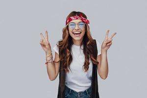 Attractive stylish young woman looking at camera and smiling while standing against grey background photo