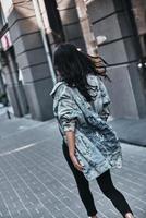 In a hurry. Rear view of young woman in denim jacket walking down the street photo