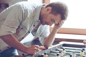 Looser. Desperate young man keeping his hand on forehead while standing over foosball in front of window photo