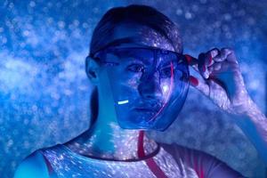 Confident young woman adjusting futuristic glasses against colorful background photo