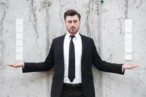 Power of business. Handsome young man in formalwear stretching out his arms while standing outdoors photo