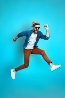 Full length of cheerful young man in casual wear shouting and gesturing while hovering against blue background photo