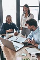 Discussing business details. Young modern colleagues in smart casual wear working together while spending time in the creative office photo