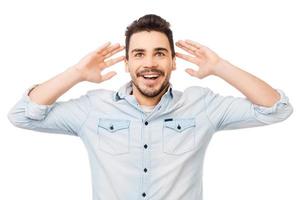 Incredible news. Portrait of surprised young man in shirt smiling while standing against white background photo