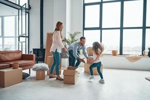 Happy young family smiling and unboxing their stuff while moving into a new apartment photo