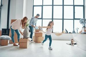 feliz familia joven sonriendo y desempacando sus cosas mientras se muda a un nuevo apartamento foto